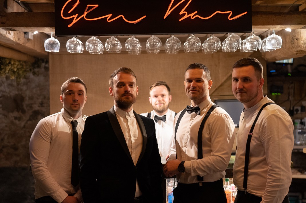 The band posing in front of a bar