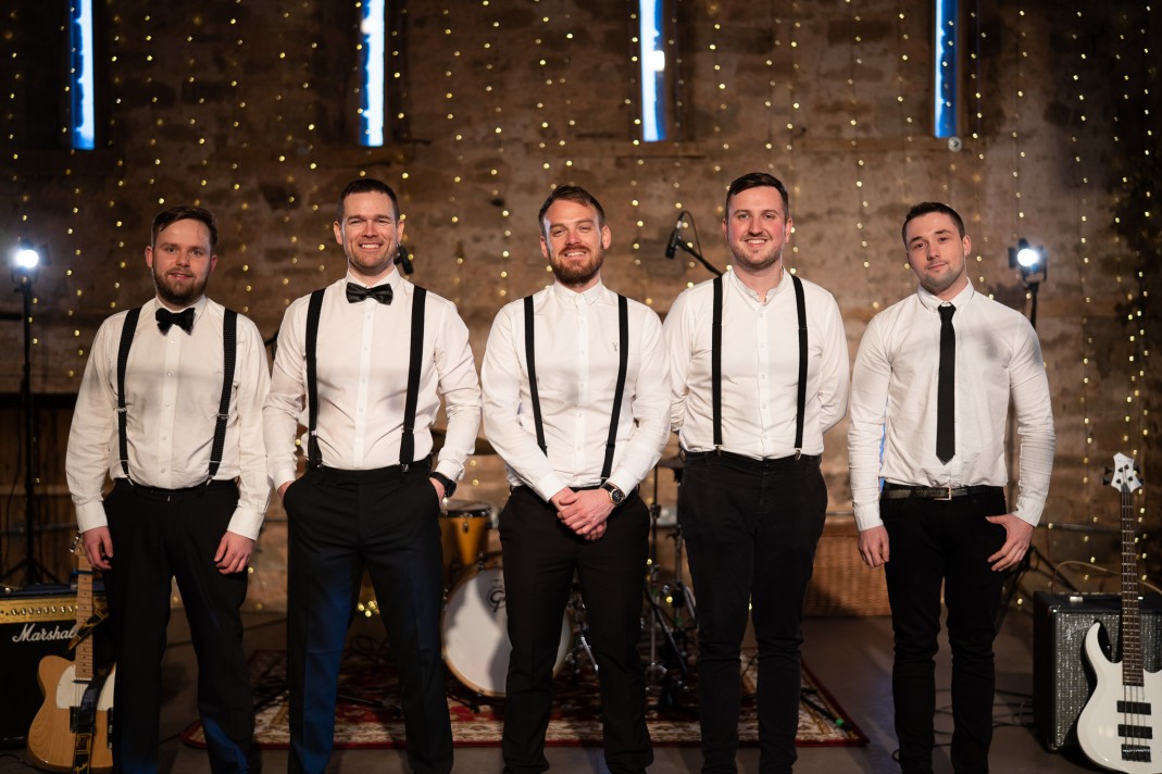 The band posing together in front of fairy lights