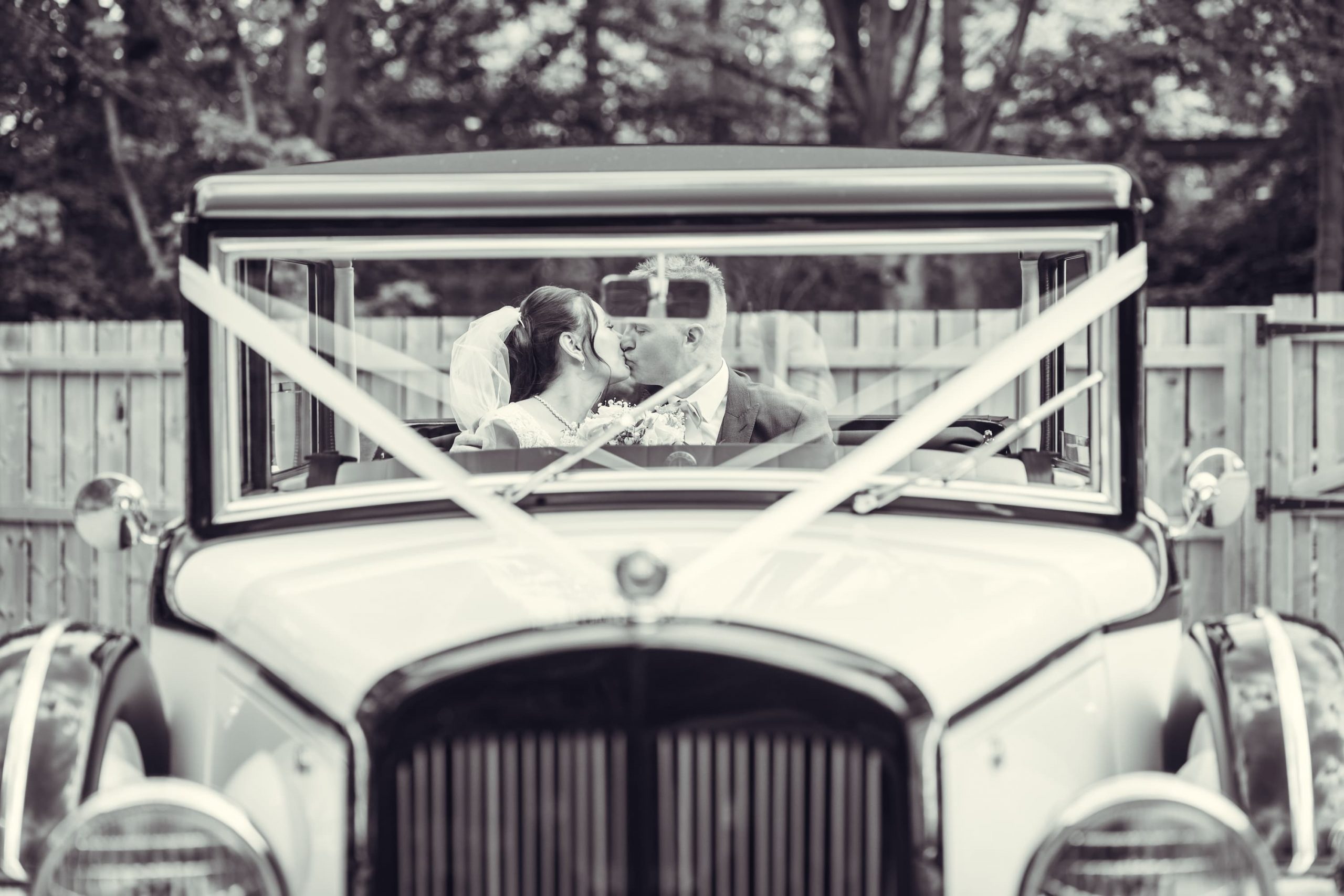 Bride and groom kiss in car