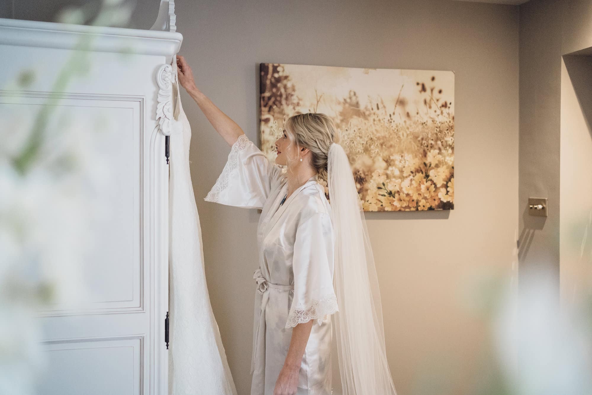 Bride picking up wedding dress off hanger